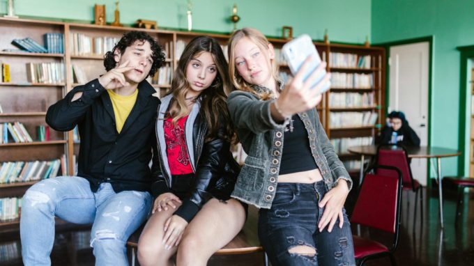 group of teenagers taking selfie in school library
